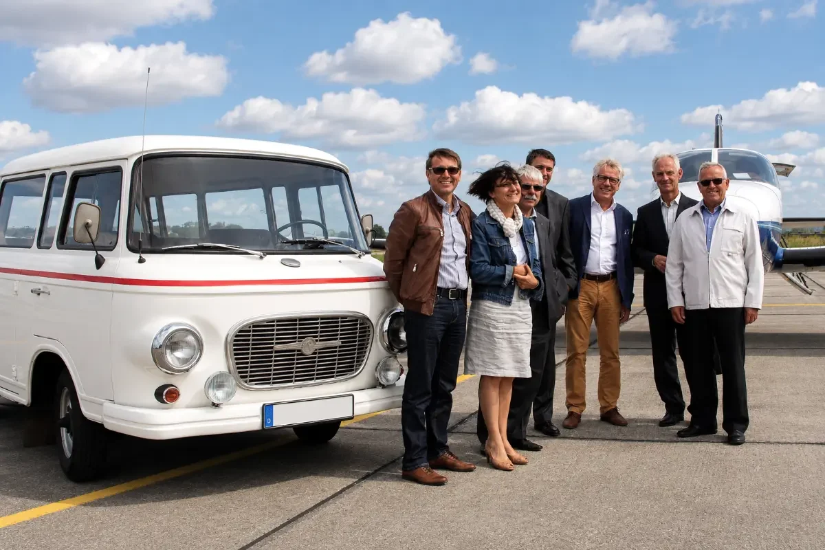 VIP Gästeshuttle auf dem Flugfeld Gäste stehen vor dem Oldtimerbus Barkas und einem Privatjet auf dem Flugfeld