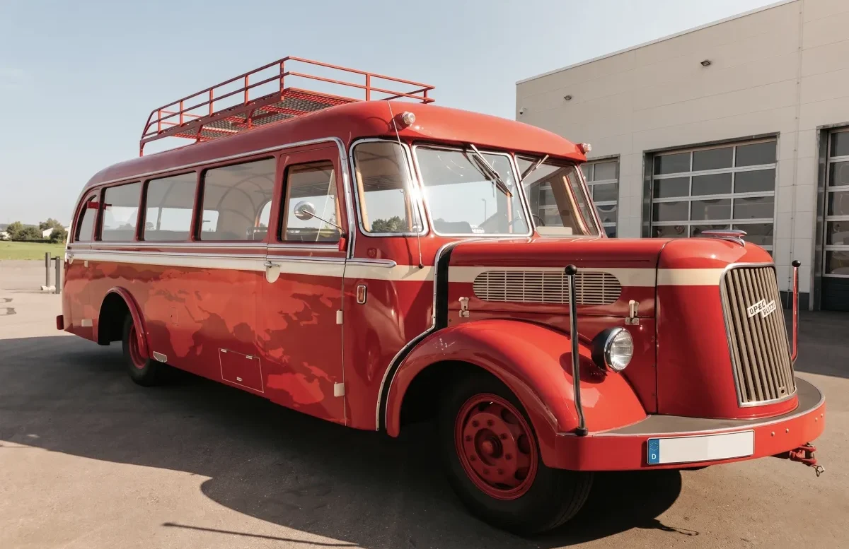 Oldtimerbus Opel Blitz Ein roter Oldtimerbus der Marke Opel Blitz steht vor einer Halle