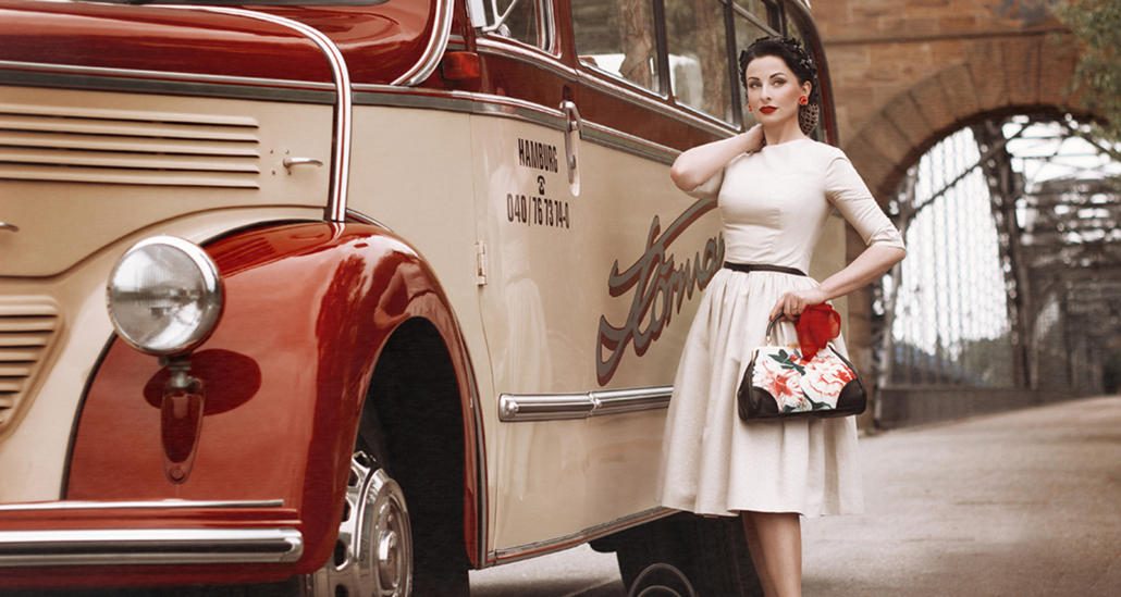 Frau im 50er Jahre Look steht vor einem Oldtimerbus der Marke Daimler Benz in Hamburg