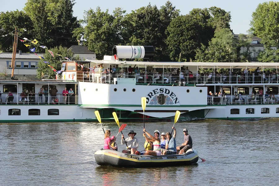 Schlauchboot mit Gästen auf der Elbe, im Hintergrund der Schauffelraddampder "Dresden"